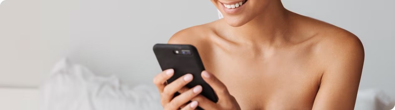 Woman smiling as she picks up her cell phone.